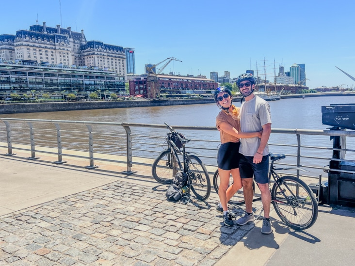 a couple posing for a picture at Puerto Madero in Buenos Aires with the woman bridge behind