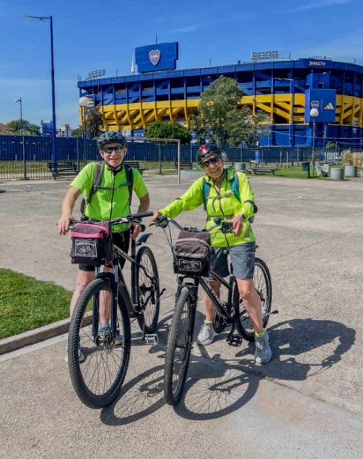 a couple exploring La Boca during a Bike tour with Biker Street. There is Boca Juniors stadium